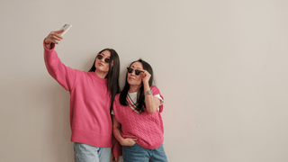 Friends taking a selfie while wearing matching pink sweaters