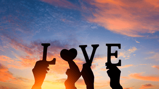 The word "Love" spelled out in front of a pastel sunset