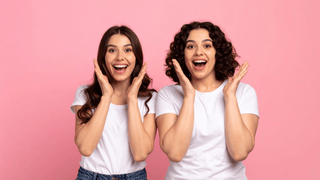 Surprised women in front of cute pink wall