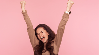Excited woman in front of pink wall
