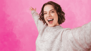 Woman taking a selfie in front of hot pink backdrop