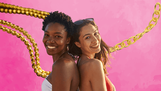 Two women posing smiling in front of permanent jewelry chain