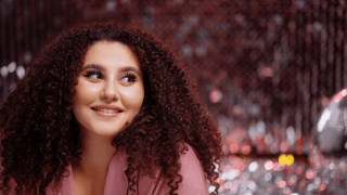 Woman in pink outfit in front of sparkly background