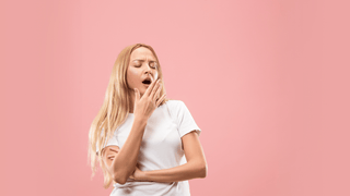 woman yawning in front of pink backdrop