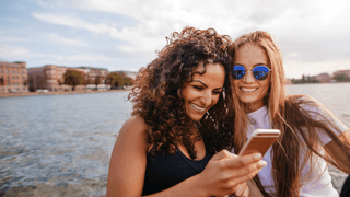 Two female friends smiling by the lake