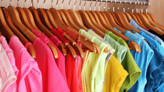 A closet with various colorful women's tops