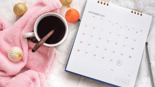 Calendar next to holiday items and light pink blanket