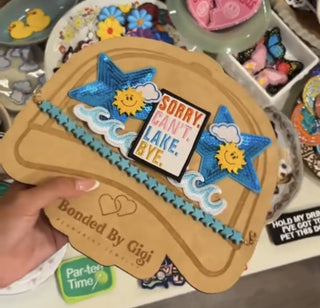 Patches and hat chain laid out on a hat board in front of an array of trucker hat patches